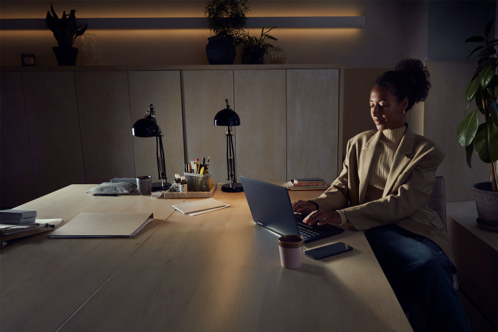 Kvinna i kavaj med take away-kaffe arbetar med laptop på kontor